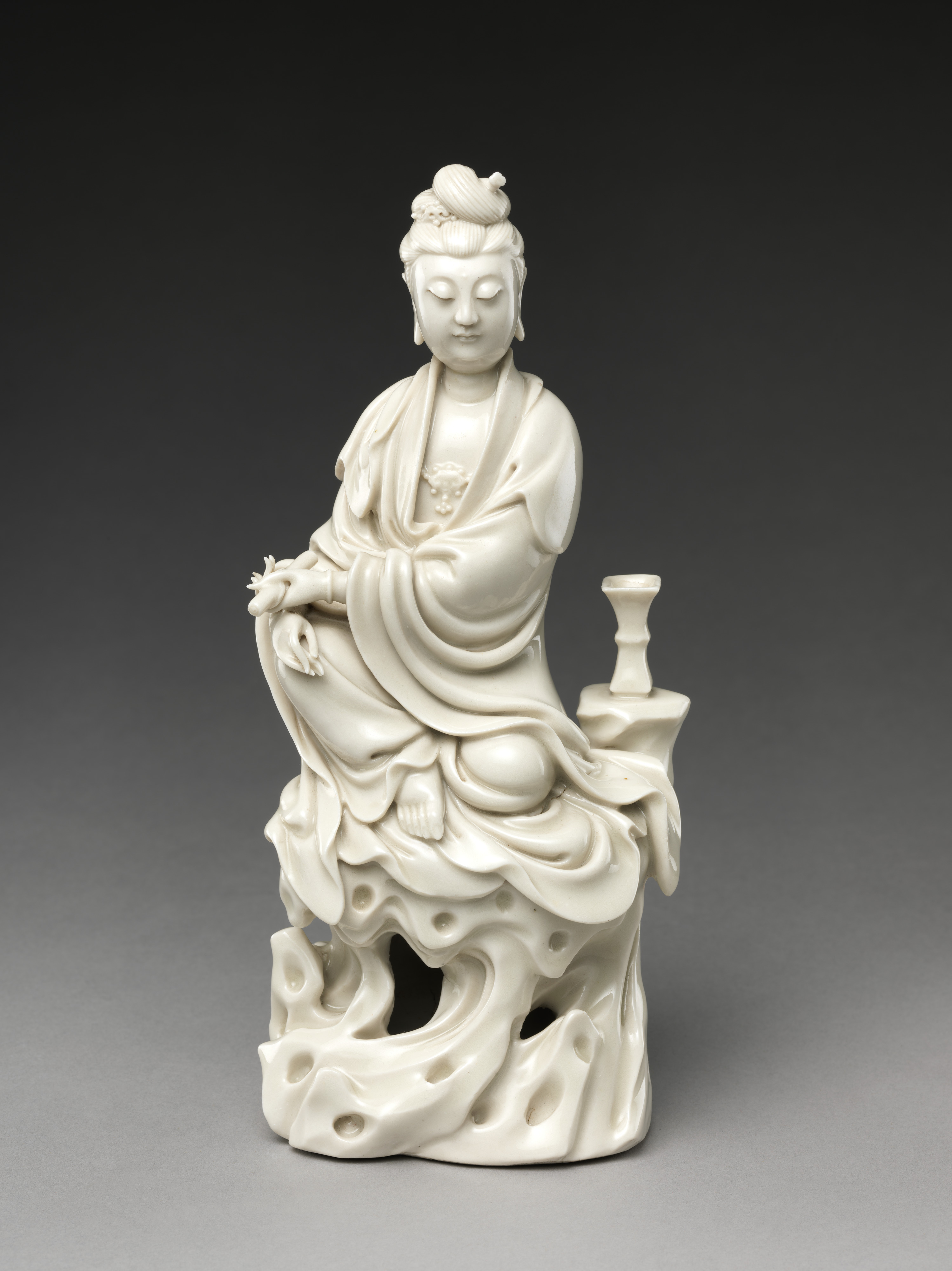 Bodhisattva Guanyin Seated on a Rock, Porcelain with ivory glaze (Dehua ware), 18th century, H. 23 cm, The Metropolitan Museum of Art, 55.111.84, Blanc de Chine